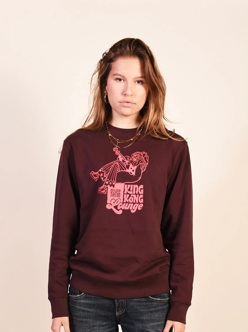 A person wearing a long-sleeved burgundy red sweater with a graphic print of King Kong.