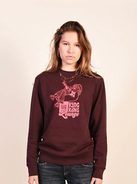 A person wearing a long-sleeved burgundy red sweater with a graphic print of King Kong.