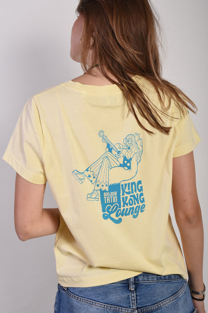 Person wearing a yellow t-shirt with a blue graphic and text on the back, standing against a plain background.