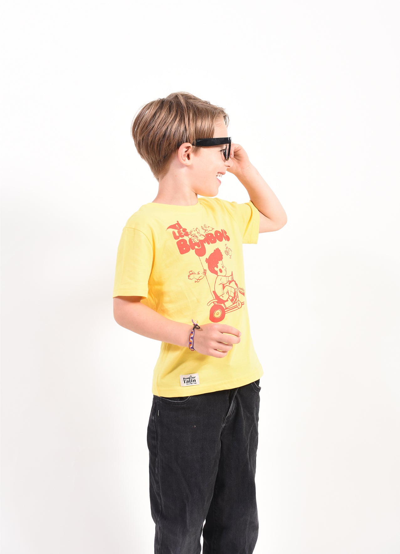 Child wearing a yellow t-shirt with a graphic design on a white background
