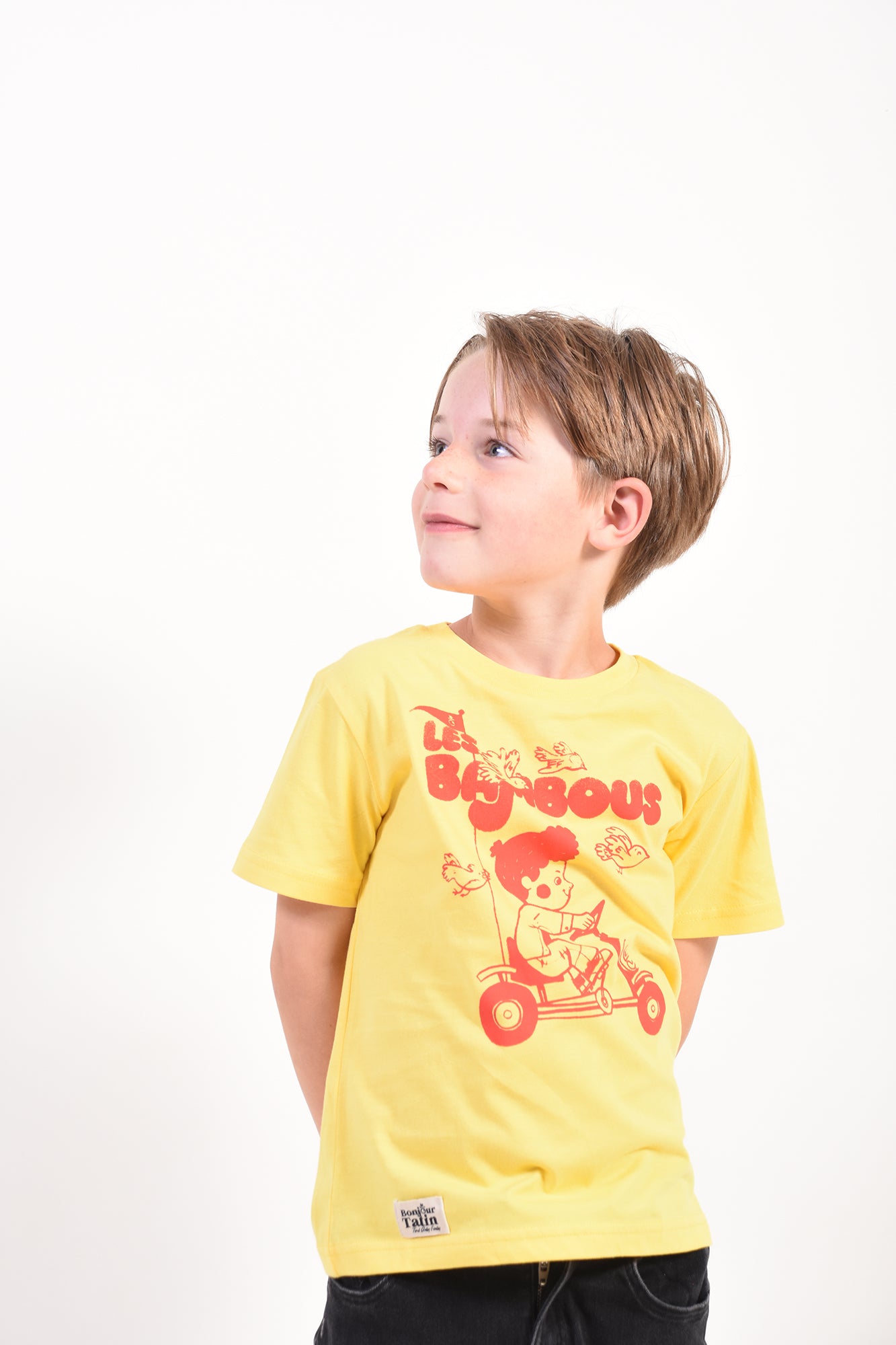 Child wearing a yellow t-shirt with red graphics on a white background