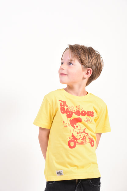Child wearing a yellow t-shirt with red graphics on a white background