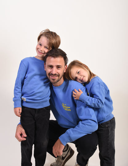Man with two children wearing matching blue sweatshirts on a white background